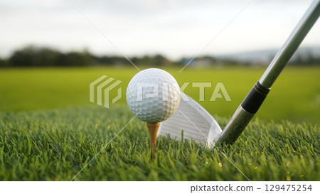 Golf clubs and balls on a green lawn in a beautiful golf course with morning sunshine. Golf clubs and balls on a green lawn in a beautiful golf course with morning sunshine. 129475254