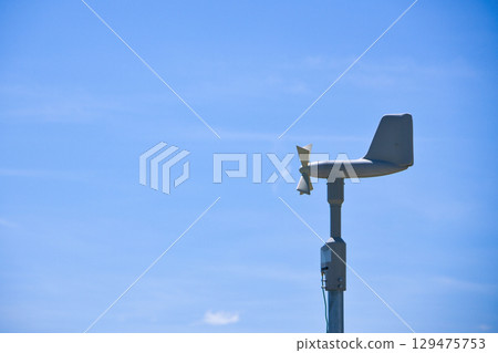 Blue sky and wind vane measuring wind speed and velocity Blue sky and wind vane measuring wind speed and velocity 129475753