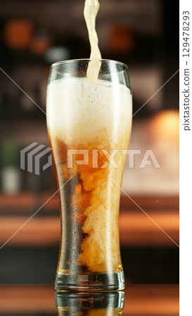 Pouring Beer into Large Glass with Blur Interior Background. Detail of Pint of Beer, Beverages Background. Vertical Aspect Ratio. 129478293