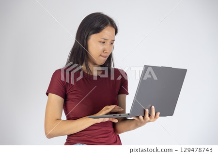 A woman is looking at a laptop and interacting with its touchpad. 129478743