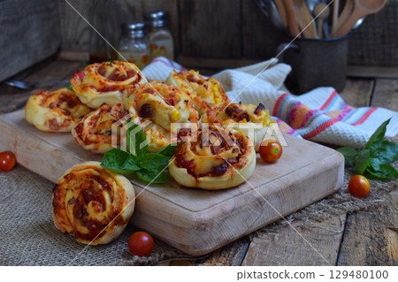 Buns of yeast dough with tomatoes, ham and cheese on a wooden background. Mini pizzas. homemade baking Buns of yeast dough with tomatoes, ham and cheese on a wooden background. Mini pizzas. homemade baking 129480100