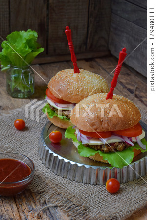 Veggie burgers with chop of eggplant, lettuce, pickled onions, tomato on a brown wooden background. Vegetarian lunch or dinner idea. Healthy food. 129480111
