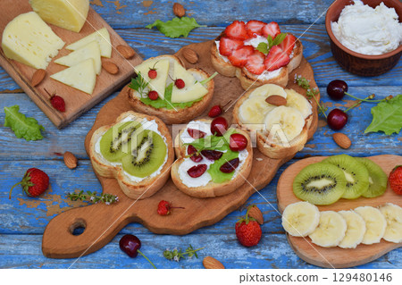 Set of healthy whole wheat bread sandwiches with fuits, vegetables, cheese and leafy green herbs on picnic wooden table. Ciabatta sandwich bar. Top view. Lunch time snacks concept. Vegetarian food Set of healthy whole wheat bread sandwiches with fuits, vegetables, cheese and leafy green herbs on picnic wooden table. Ciabatta sandwich bar. Top view. Lunch time snacks concept. Vegetarian food 129480146
