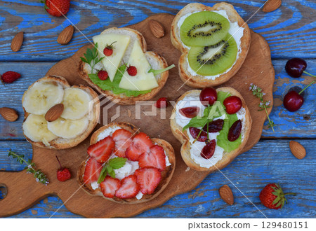 Set of healthy whole wheat bread sandwiches with fuits, vegetables, cheese and leafy green herbs on picnic wooden table. Ciabatta sandwich bar. Top view. Lunch time snacks concept. Vegetarian food 129480151