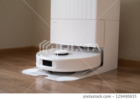 Robot vacuum is cleaning the room starting with dry vacuuming and then switching to mopping for a complete floor cleanup. 129480655