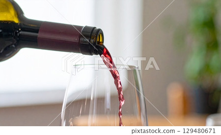 Close-up of wine being poured into a decanter in soft natural light 129480671