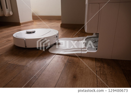 Task done the robot vacuum returns smoothly to its home base to recharge batteries and empty the dustbin without human help. 129480673