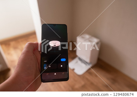 Busy freelancer uses phone app to control robot vacuum for quick and efficient home cleaning while working Busy freelancer uses phone app to control robot vacuum for quick and efficient home cleaning while working 129480674