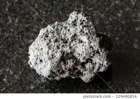sample of raw pumice mineral on black granite 129480854