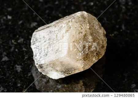 sample of raw phenakite mineral on black granite 129480865