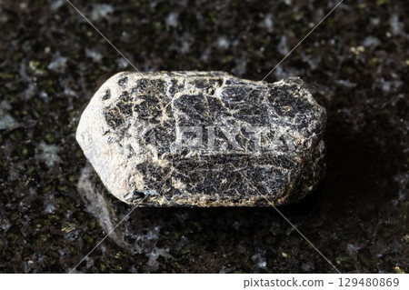 sample of raw augite mineral on black granite 129480869