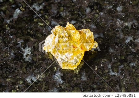 sample of raw sinhalite mineral on black granite 129480881