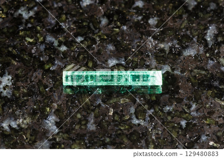sample of raw emerald crystal on black granite 129480883