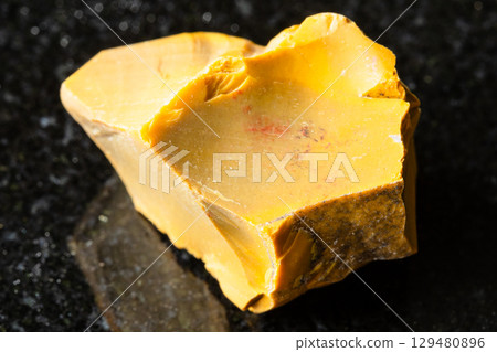 sample of raw yellow mookaite mineral on black 129480896