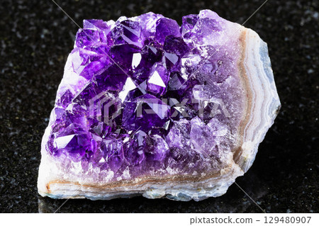 raw geode of amethyst mineral crystals on black 129480907