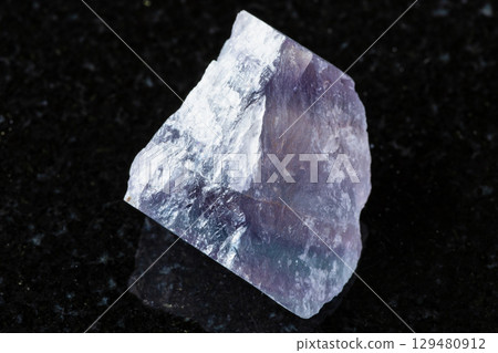 raw purple striped fluorite mineral on black 129480912