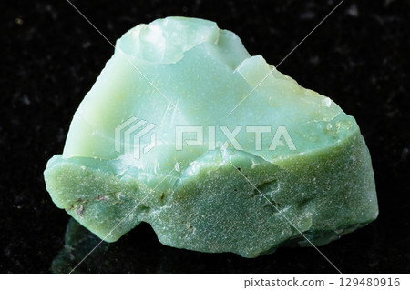 sample of raw chrysoprase mineral on black granite 129480916