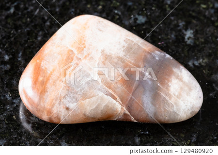 sample of tumbled nepheline rock on black granite sample of tumbled nepheline rock on black granite 129480920