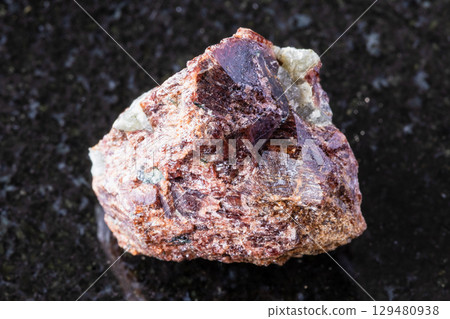 sample of raw eudialyte mineral on black granite 129480938