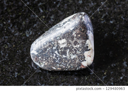 sample of tumbled trachybasalt rock on black 129480963