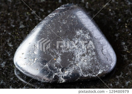 sample of tumbled ilmenite mineral on black 129480979