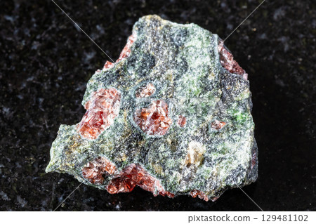 sample of pyrope garnets in rough rock on black 129481102