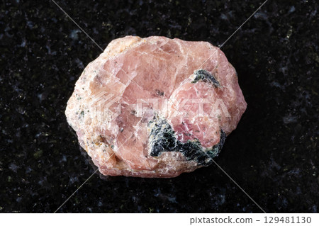 sample of raw pink ruby mineral on black granite 129481130