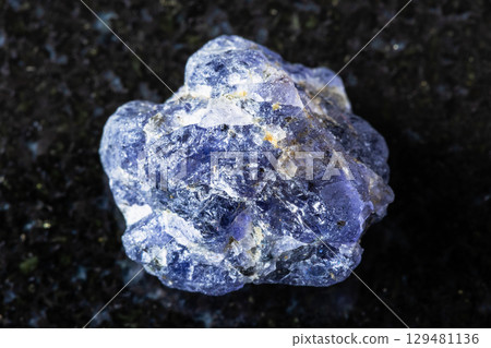 sample of raw iolite mineral on black granite 129481136