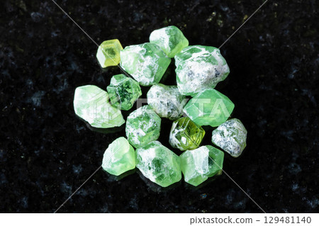 many raw demantoid crystals on black granite many raw demantoid crystals on black granite 129481140