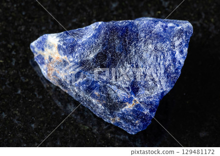 sample of raw sodalite rock on black granite 129481172