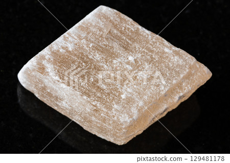sample of raw selenite mineral on black granite 129481178