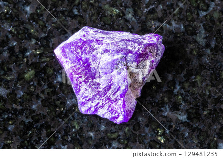 sample of raw sugilite mineral on black granite 129481235