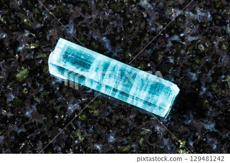 sample of raw indigolite crystal on black granite 129481242
