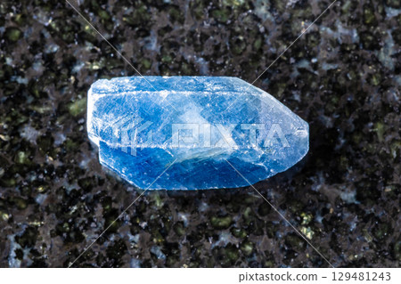 raw single blue sapphire crystal on black granite 129481243