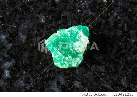 sample of rough emerald mineral on black granite sample of rough emerald mineral on black granite 129481253