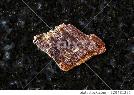 sample of raw rutile mineral on black granite 129481255