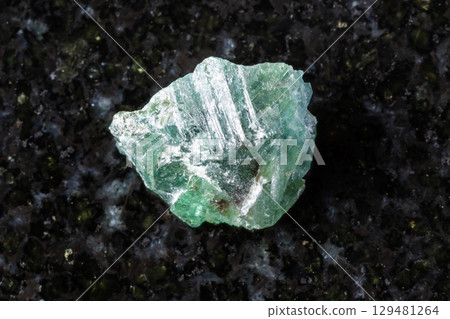 raw green alexandrite crystal in daylight on black 129481264