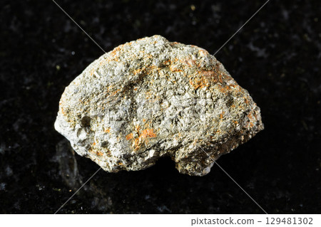 sample of uncut pyrite rock on black granite 129481302