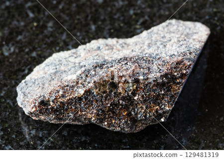 sample of raw phlogopite mica on black granite 129481319