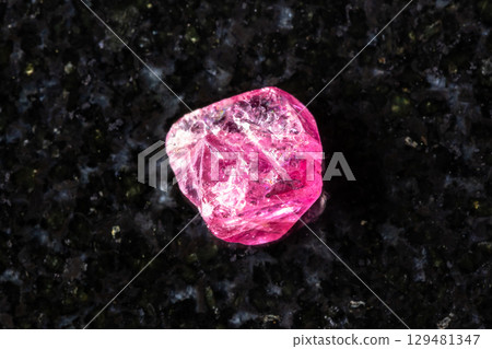sample of raw pink spinel mineral on black granite 129481347