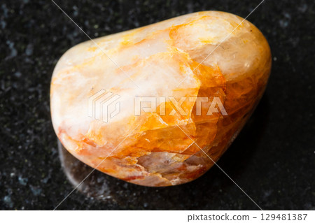 sample of polished orange quartz rock on black 129481387