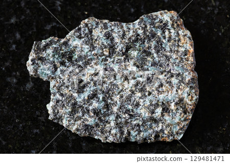 sample of raw gabbro-norite rock on black granite 129481471