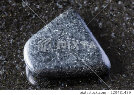 sample of tumbled dolerite rock on black granite sample of tumbled dolerite rock on black granite 129481489