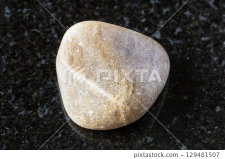 sample of tumbled cryolite rock on black granite sample of tumbled cryolite rock on black granite 129481507