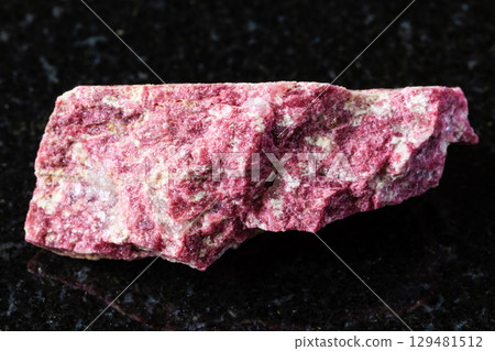 sample of raw thulite rock on black granite sample of raw thulite rock on black granite 129481512