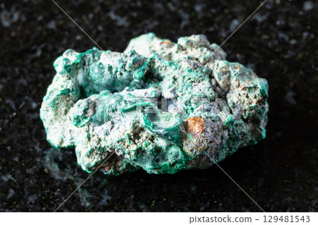 sample of raw malachite rock on black granite 129481543