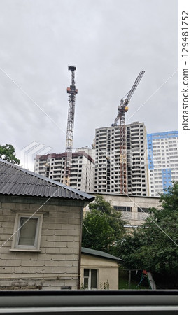 Construction site with high-rise buildings and tower cranes against a cloudy sky. Concept of urban development, growth and modern architecture Construction site with high-rise buildings and tower cranes against a cloudy sky. Concept of urban development, growth and modern architecture 129481752