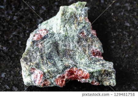 sample of pyrope garnets in raw rock on black 129481758