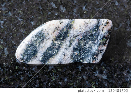 sample of tumbled gneiss rock on black granite 129481793