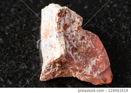 sample of raw red jasper rock on black granite sample of raw red jasper rock on black granite 129481819